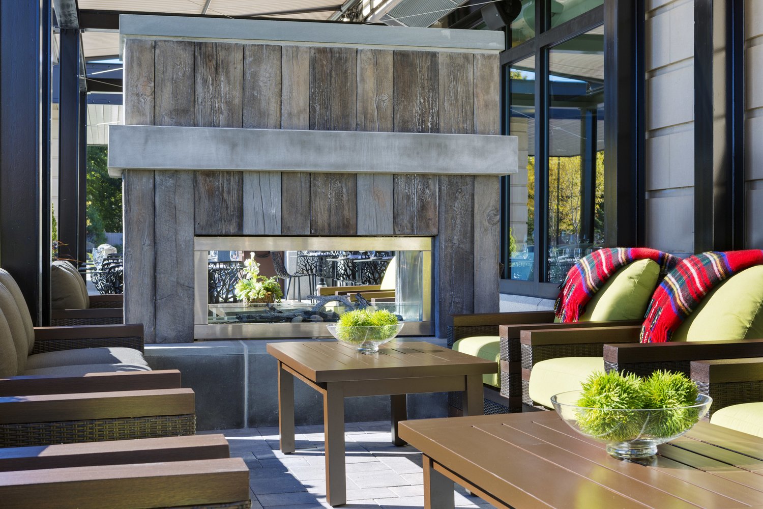 A lounge area with soft seating and bright pillows around a fireplace.